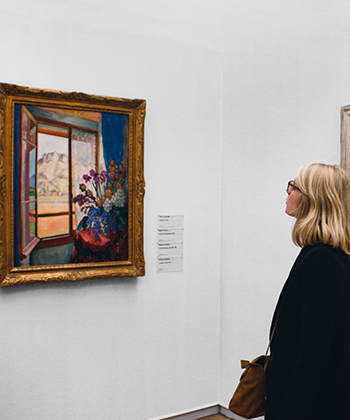 A woman looking at a painting on a gallery 