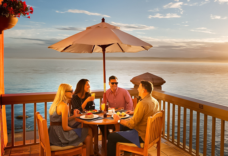 View of a group of friends having dinner at a balcony next ti the sea