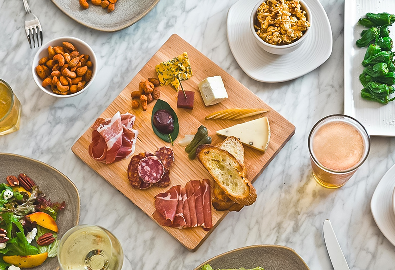 Top view of a charcuterie board and some snacks around it