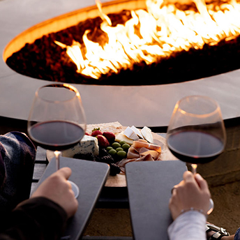 View of a couple drinking wine next to a firepit