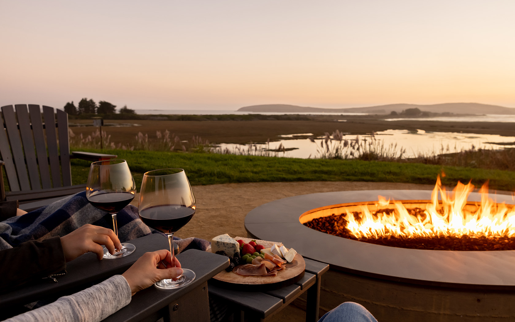 View of a couple drinking wine next to a fire pit with a romantic view 