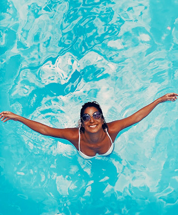 above photo of a woman smiling while she is enjoying the pool