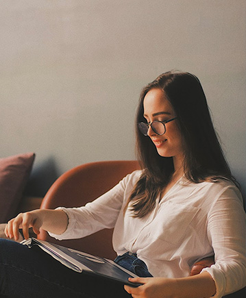lady wearing black glasses sitting reading a magazine
