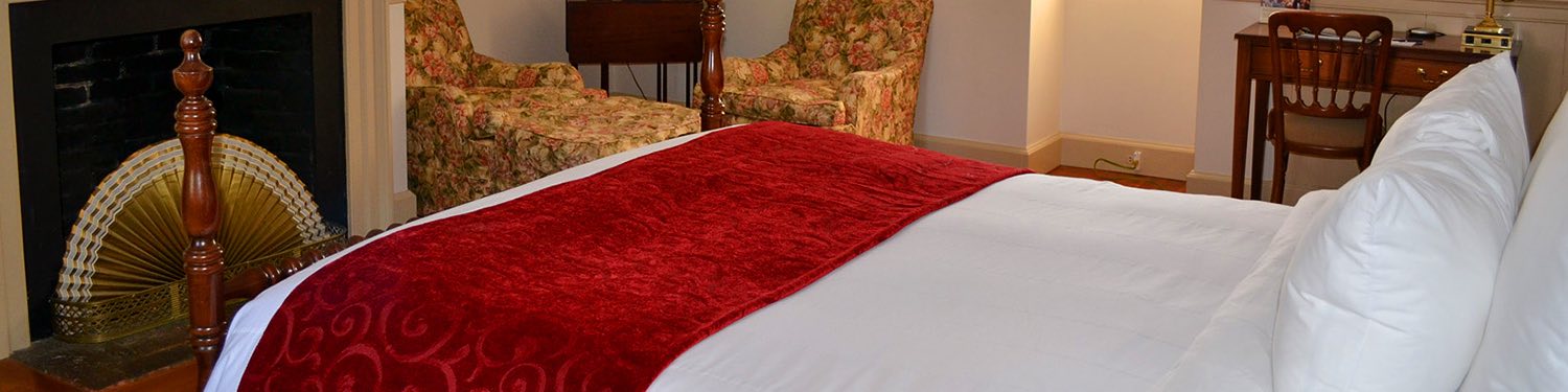 Guest room with bed with white sheets & red accent
