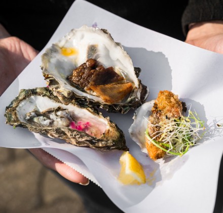 three oysters and a lemon wedge on a plate