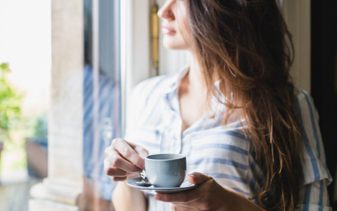 woman holding a coffee mug looking out a window