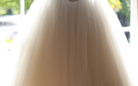 wedding dress hanging in front of a window