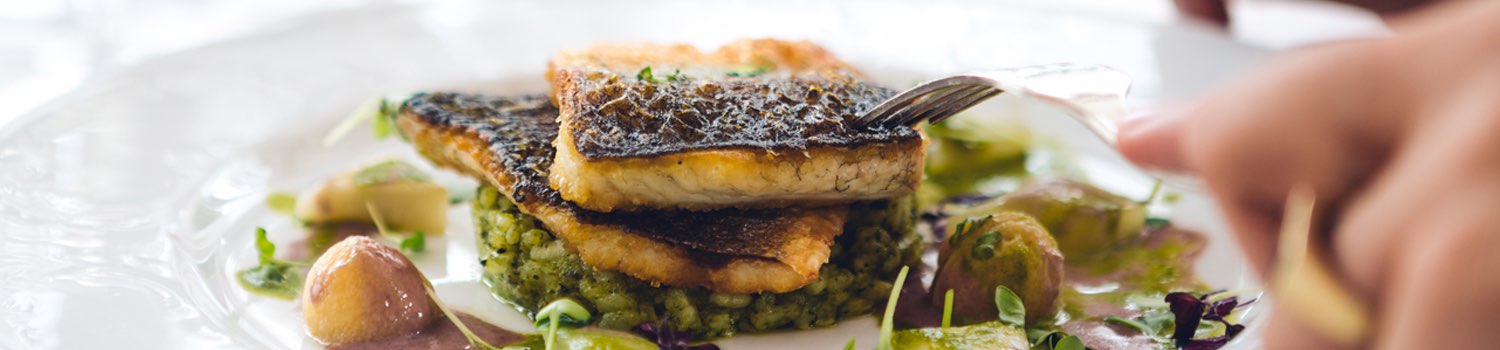 close up of a person cutting into a blacked fish meal