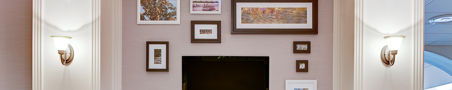 a wall with various sized picture frames and a tv on the wall