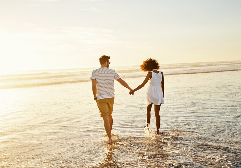 a couple holding hands and walking to the sea