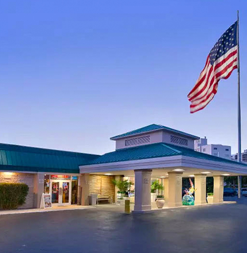 exterior view of the hotel building and a US flag at sunset