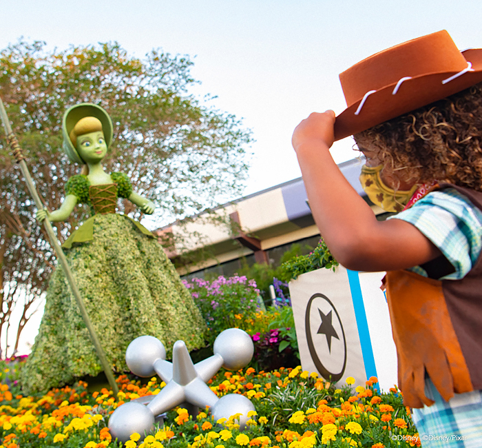 A little girl looking at topiary of a Disney character
