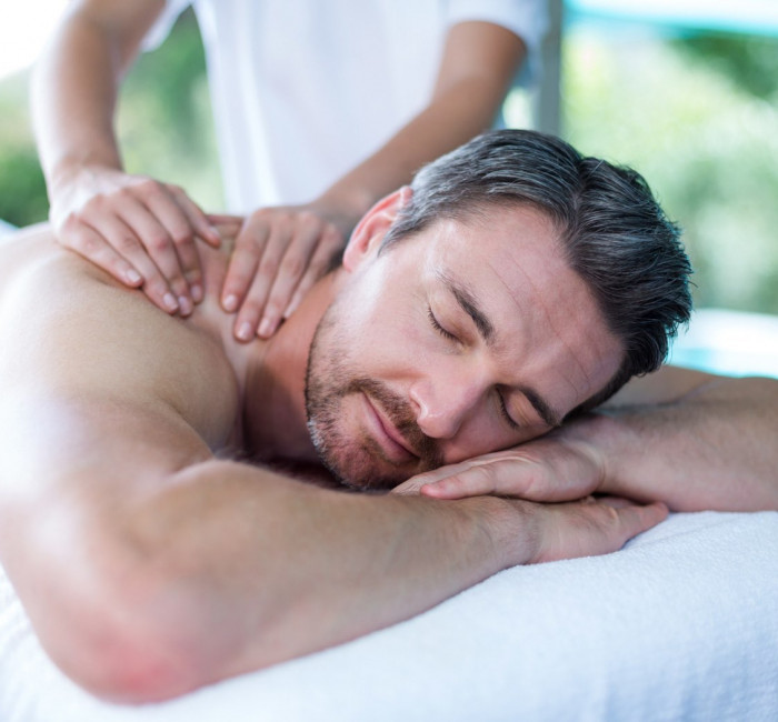 man with beard laying on table receiving a massage