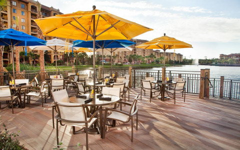 deck area with tables and chairs under yellow and blue umbrellas