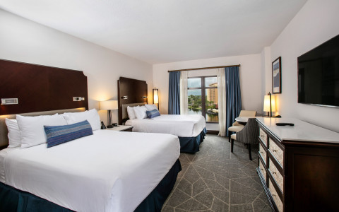 hotel room with two queen beds with white and blue linens