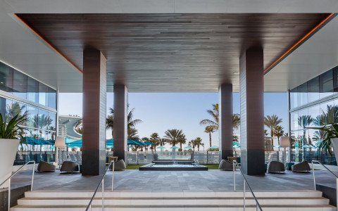 Hotel entrance with view of pool and palm trees