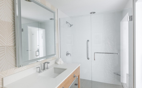White bathroom with vanity, sink & glass door shower