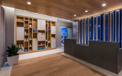 Salon black front desk with products sitting on wooden shelving on wall