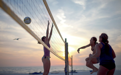 Friends playing volleyball with sun setting in the back