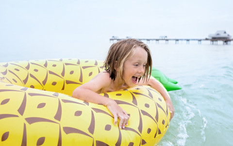 Little boy on pineapple float in the beach water