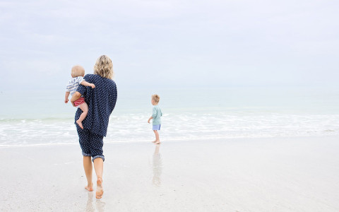 Woman with two kids walking toward ocean shore