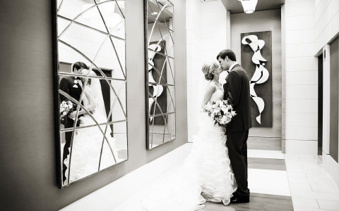 Black and white image of wedding couple kissing indoors