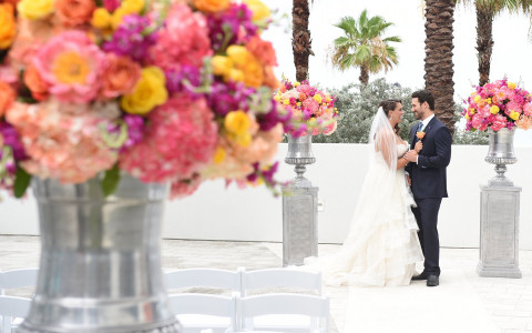 Wedding couple standing in courtyard with roses bouquets
