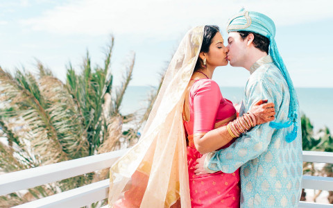 Kissing wedding couple dressed in authentic indian wedding garments