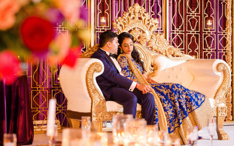 Wedding couple dressed in indian garments sitting on couch