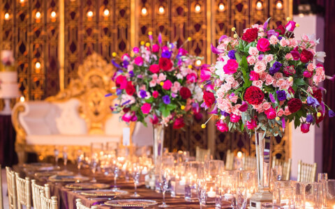 Long table set up for wedding reception with multiple shades of pink flowers