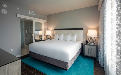hotel room with king bed and teal rug underneath