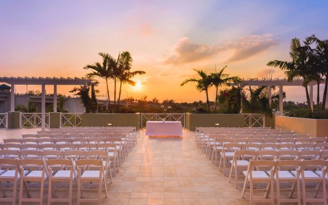 rows of chairs lined up for an outside wedding ceremony outside at sunset