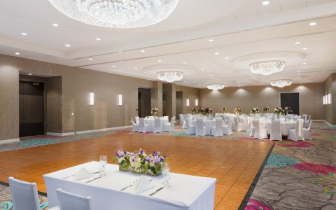 a large ballroom with crystal light fixtures set up for a wedding reception with a dancefloor