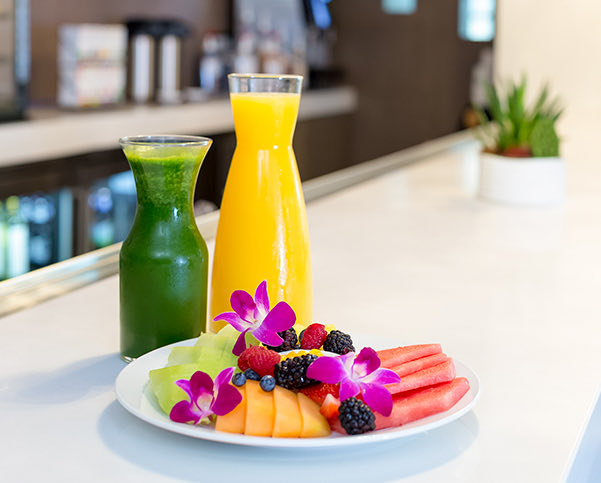 two carafes with OJ and a green juice with 