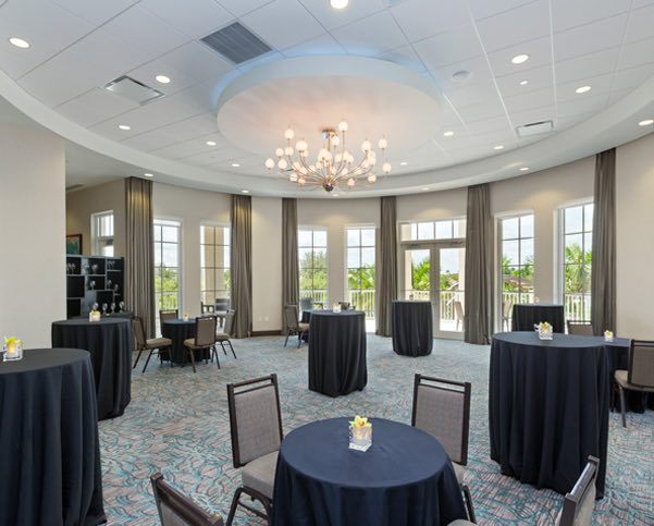 Event venue with spaced out small round chairs and tables