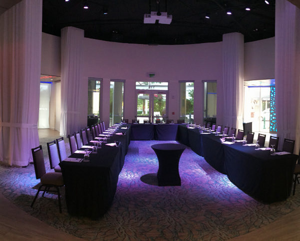 event venue with tables in a U-shape and purple lights