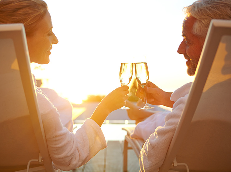 an older couple sipping champagne by the beach lounging in beach chairs