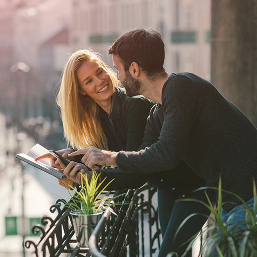 a man and woman deciding which attraction to visit on a balcony