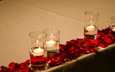 table decorated with tea light candles and red rose petals