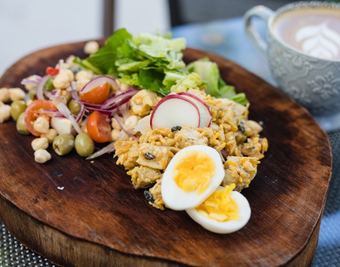 gallery image of different salads on a wooden plate and a cup of coffee next to it