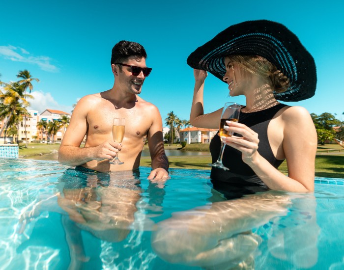 gallery image of a couple in the pool holding glasses of champagne