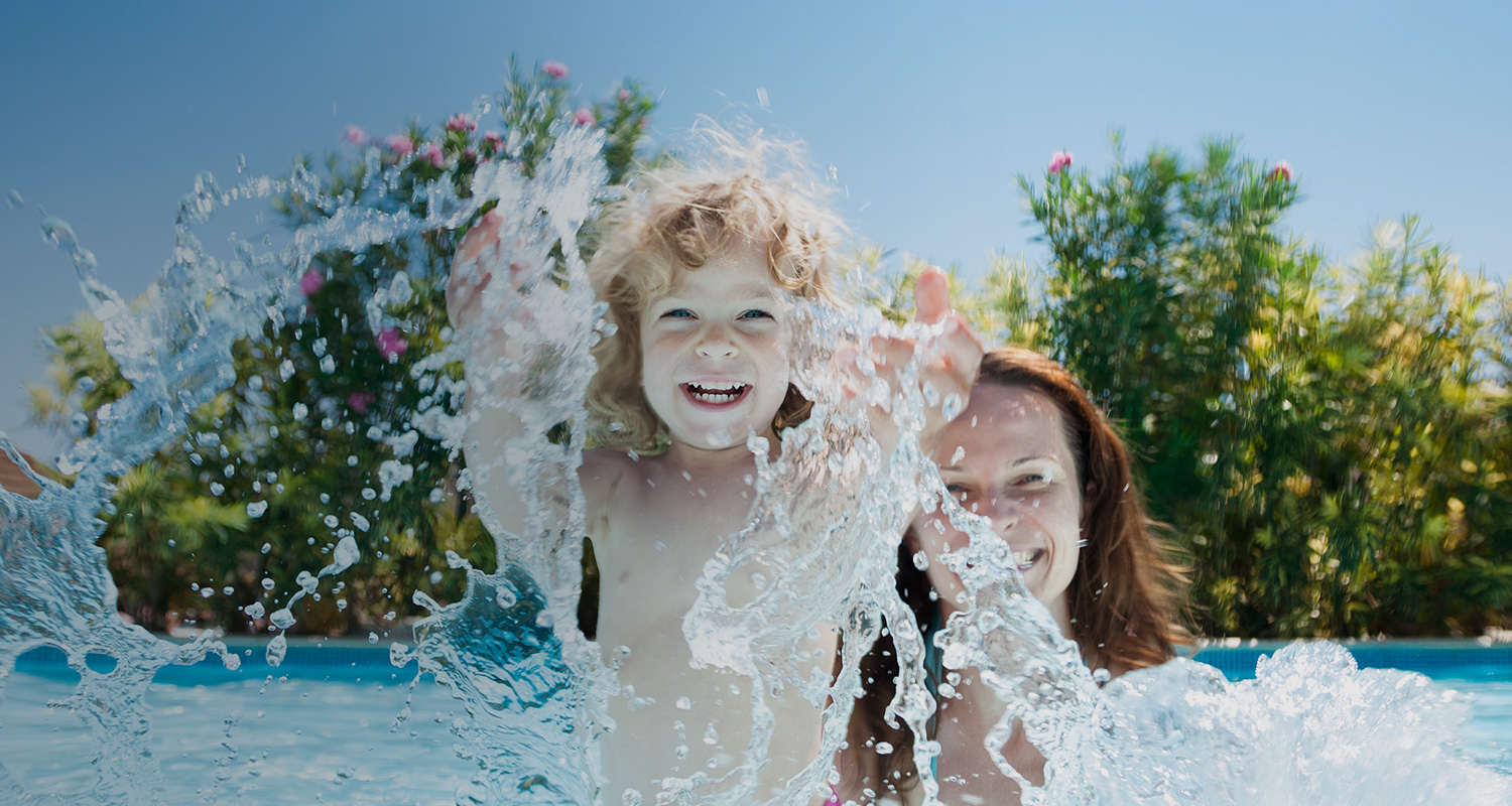 little boy splashing in water with mom