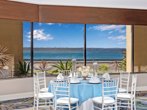 Harborside venue space with white and blue table set up with views to the sea