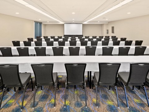 Bay Room meeting space with tables, chairs and a screen
