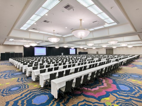 Pacific Ballroom meeting space with two screens, tables and chairs