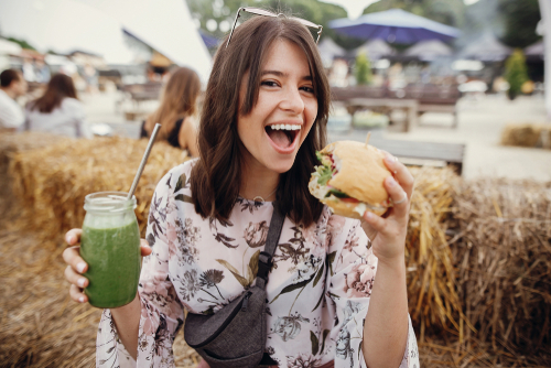 woman holding veggie burger and green juice