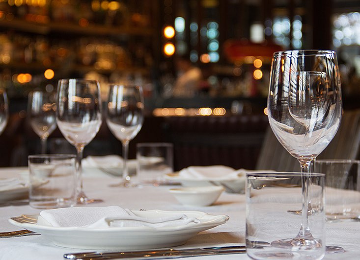 dining table setup for a meal with white plates and glassware