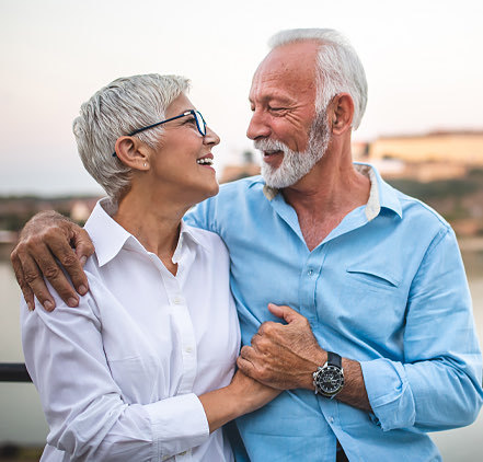 older man and woman couple happily looking at each other and holding hands