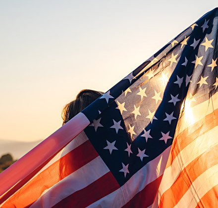 a woman has an American flag at sunset