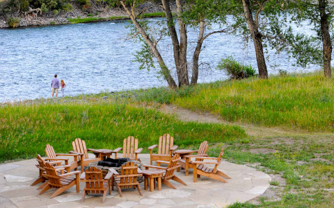 wooden lawn easy chairs around a fire-pit overlooking the river